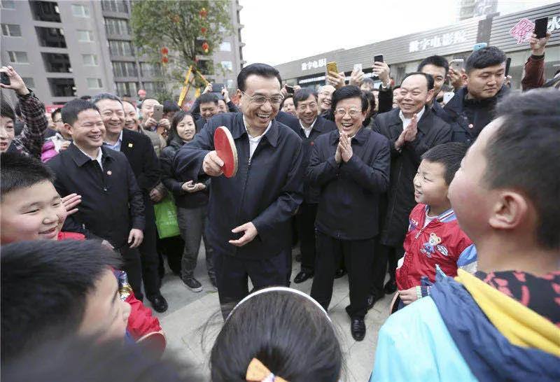 图为李克强在贵阳考察时,一群孩子围住总理“邀约”打乒乓球。